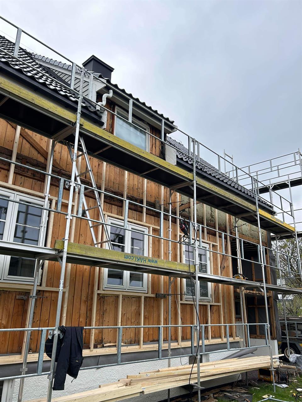 A timber facade behind scaffolding, half clad