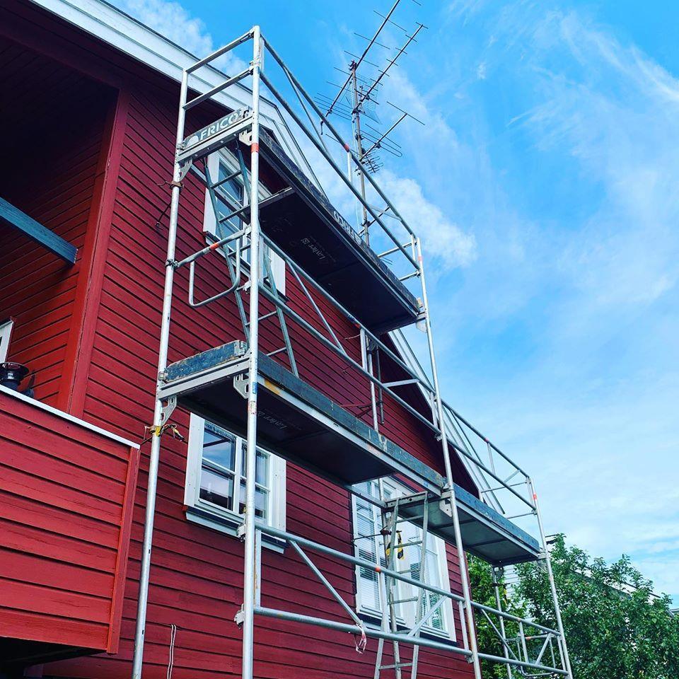 Scaffolding on a red timber house against a blue sky