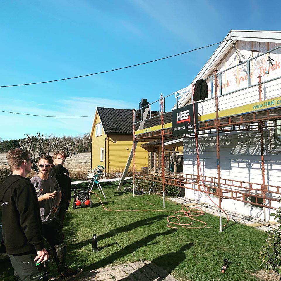The crew on a lawn beside a yellow house in scaffolding